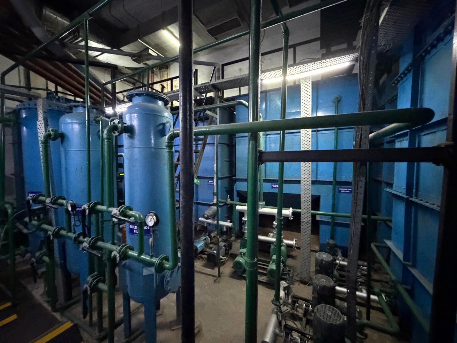Treatment vessels with valve headers and pumps in front of a fabricated tank