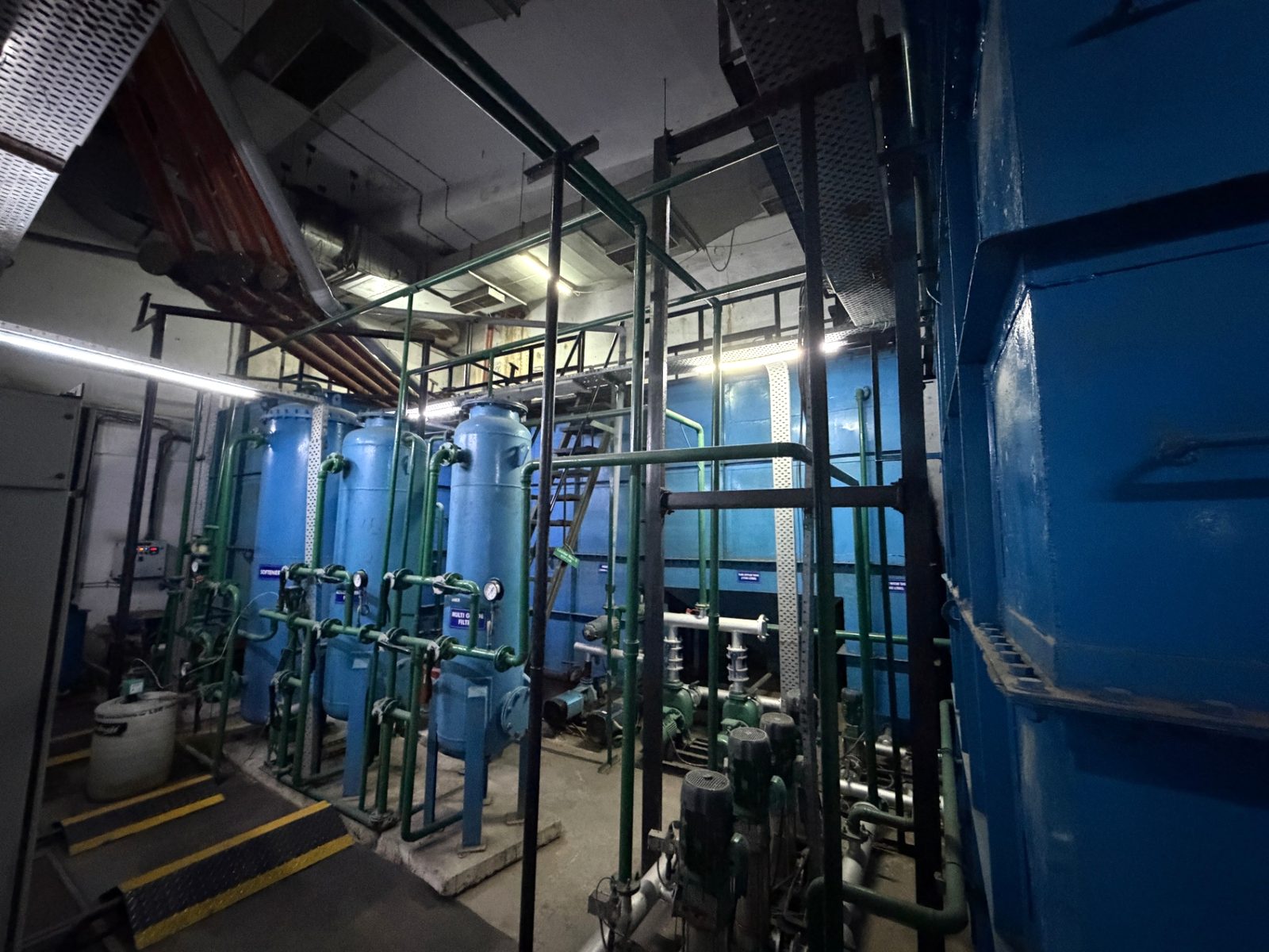 Row of blue treatment vessels with pumps and green interconnecting pipework