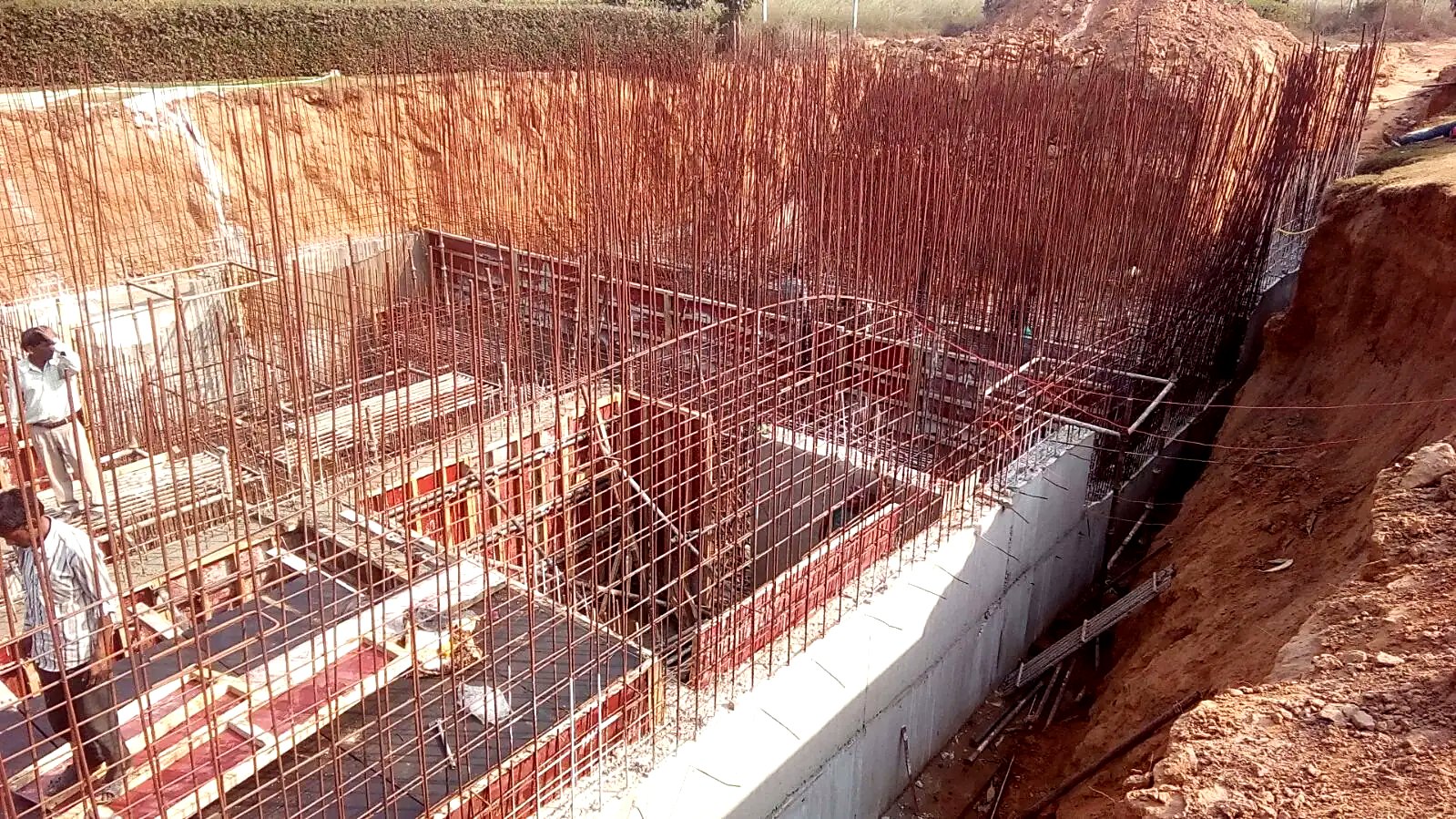 Cast concrete treatment tank walls with reinforcement projecting for upper sections