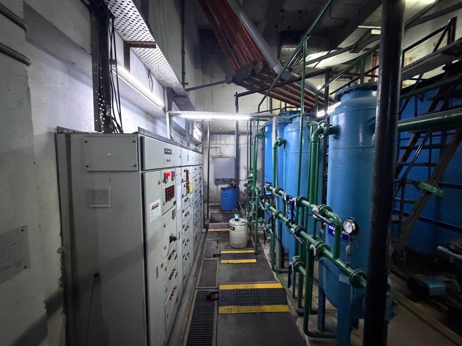 Electrical control panels facing a line of treatment vessels in the plant room