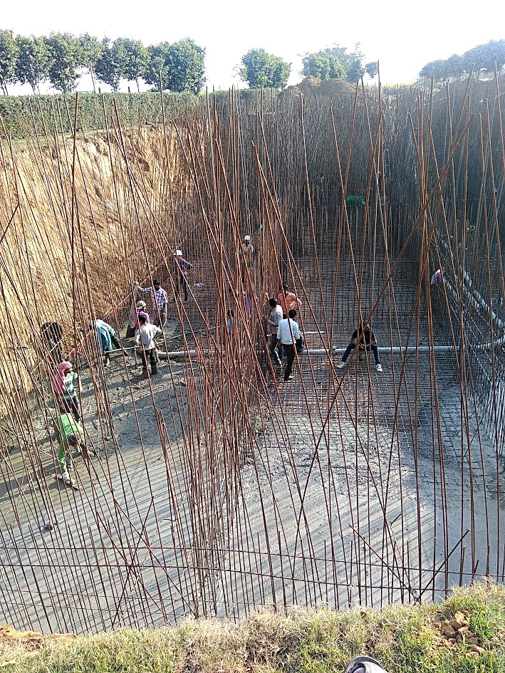 Workers placing concrete over dense raft reinforcement for a sewage treatment plant base slab